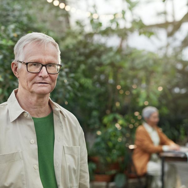 Person stretching outdoors, looking calm and focused, with a blurred natural background.